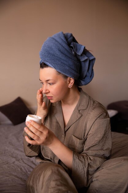 Close up view of woman with cream for face at home siting at coach look at mirror