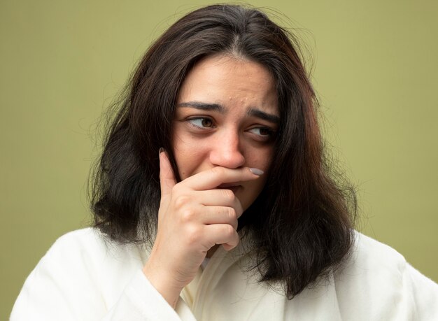 Close-up view of young ill woman wearing robe isolated on olive green wall