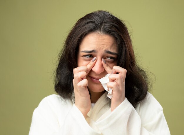 Close-up view of young ill woman wearing robe isolated on olive green wall