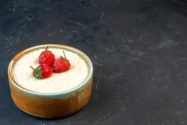 Close up view of yummy breakfast with strawberries in a bowl on the right side on dark color background with free space