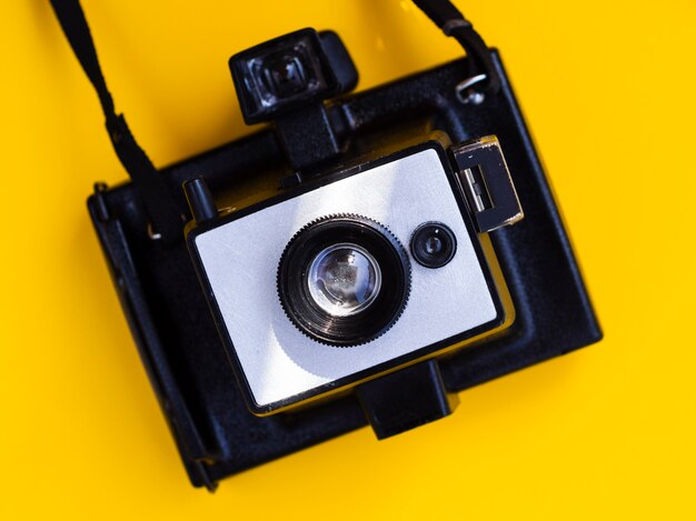 Close-up of a vintage photo camera with yellow background