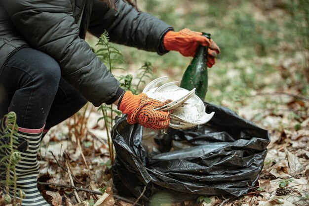 Крупный план добровольца, убирающего на природе стекло, пластик и другой мусор