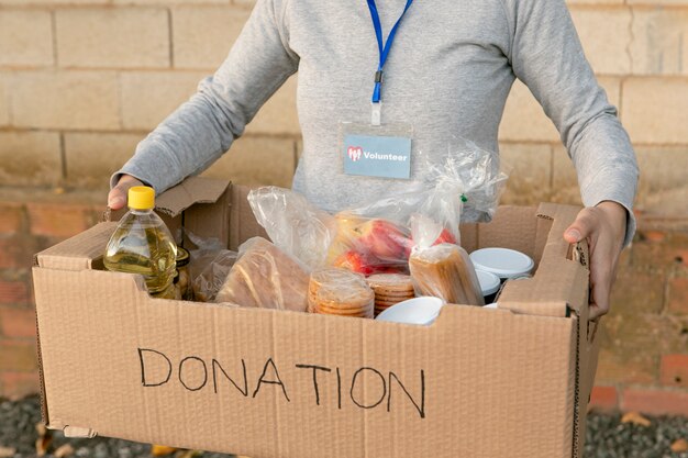Крупным планом волонтер, держащий коробку с едой