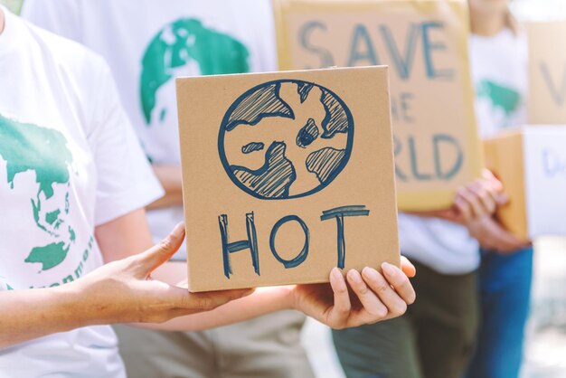 오염생태계에너지와 쓰레기에 대한 세계 환경의 날 캠페인 지구의 날 연설 사인을 들고 있는 자원 봉사자를 닫습니다.