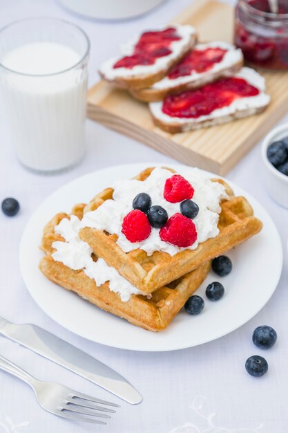 Close-up of waffle with strawberries and milk on table