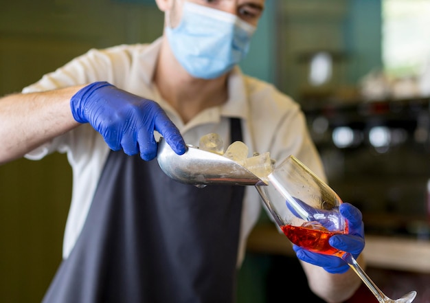 Free photo close-up waiter with gloves preparing drink