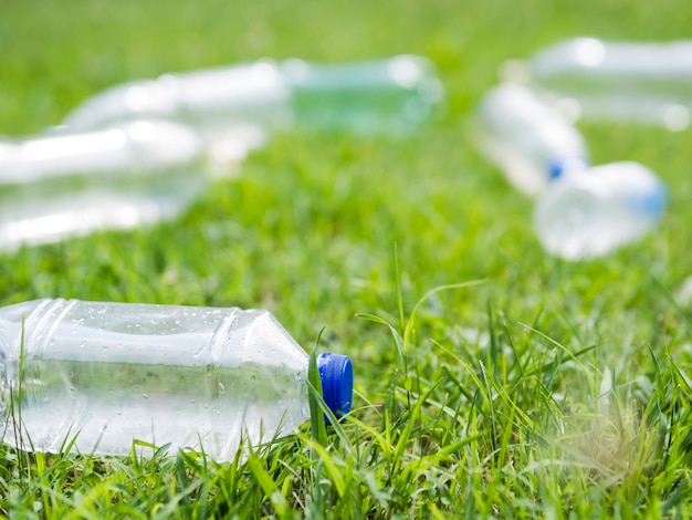 公園の芝生の上の廃プラスチック水のボトルのクローズアップ