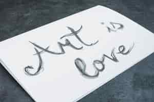 Foto gratuita il primo piano di acquerello disegnato a mano 'arte è amore' testo su carta bianca