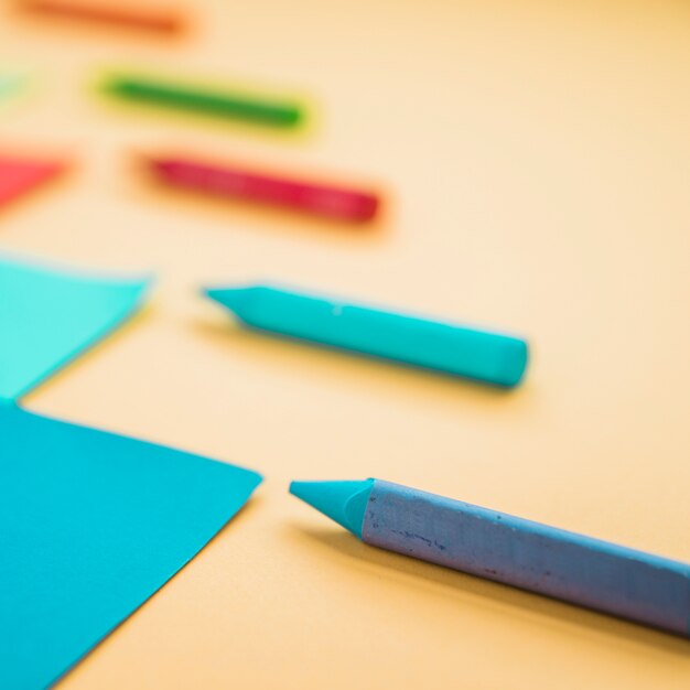 Close-up of wax crayon color and card paper against yellow background