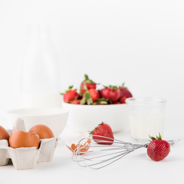 Close-up whisk with strawberries and eggs