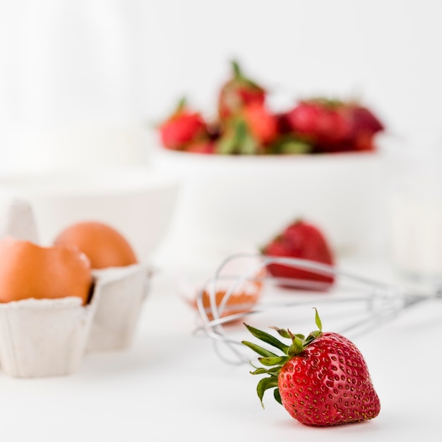 Close-up whisk with strawberries and eggs