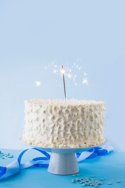 Close-up of white birthday cake with burning sparkler