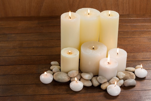 Close- up of white candles and pebbles stone on wood