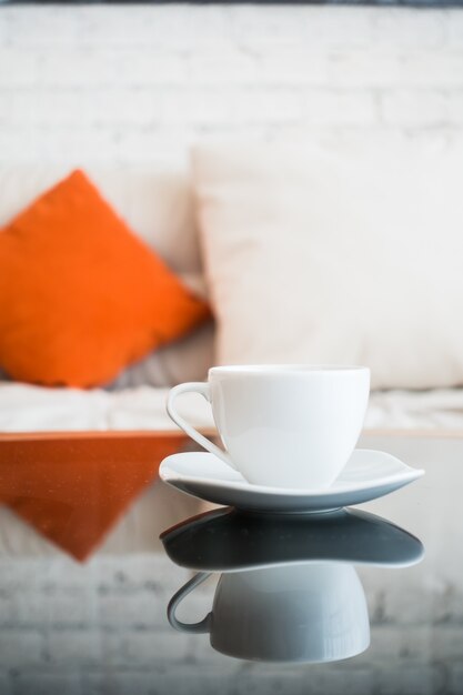 Close-up of white cup with sofa background