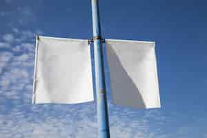 Free photo close-up of white lamp post banner poster against blue sky