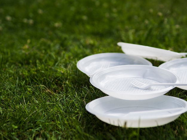 Foto gratuita primo piano del piatto e della forcella di plastica bianchi su erba al parco