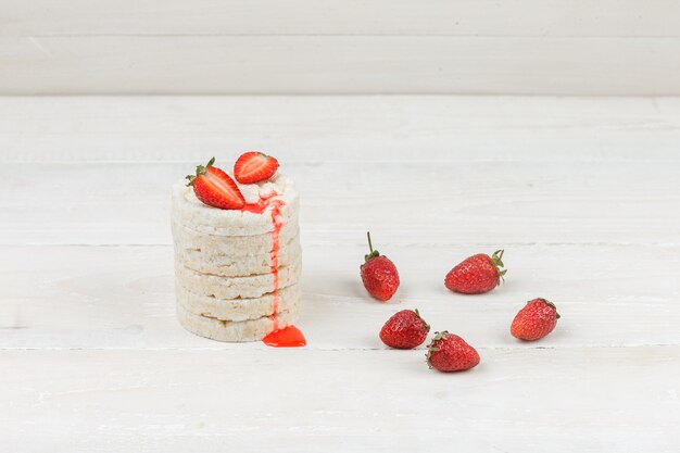 Close-up white rice cakes with strawberries on white wooden board surface. horizontal