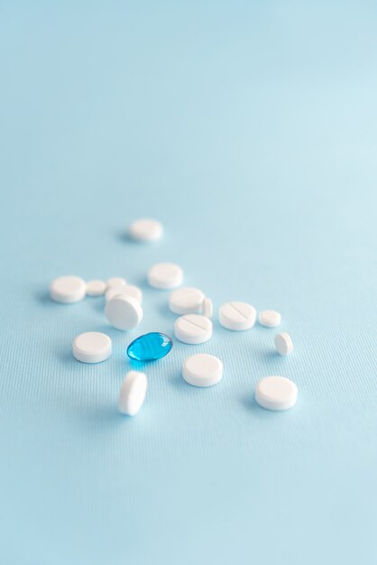 Close up of white tablets with one blue capsule