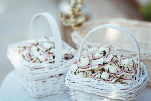 Primo piano del cesto di vimini bianco con decorazioni per gli ospiti al ricevimento di nozze.