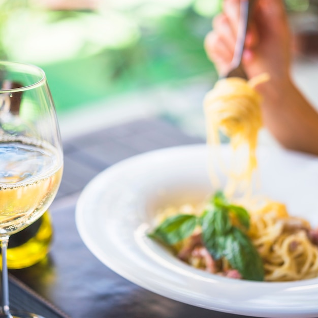 Free photo close-up of a wineglass with person eating spaghetti