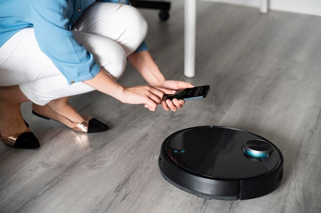 Close up woman activating vacuum cleaner with phone