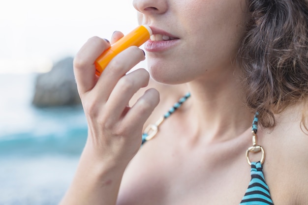 Free photo close-up of woman applying balsam on lips