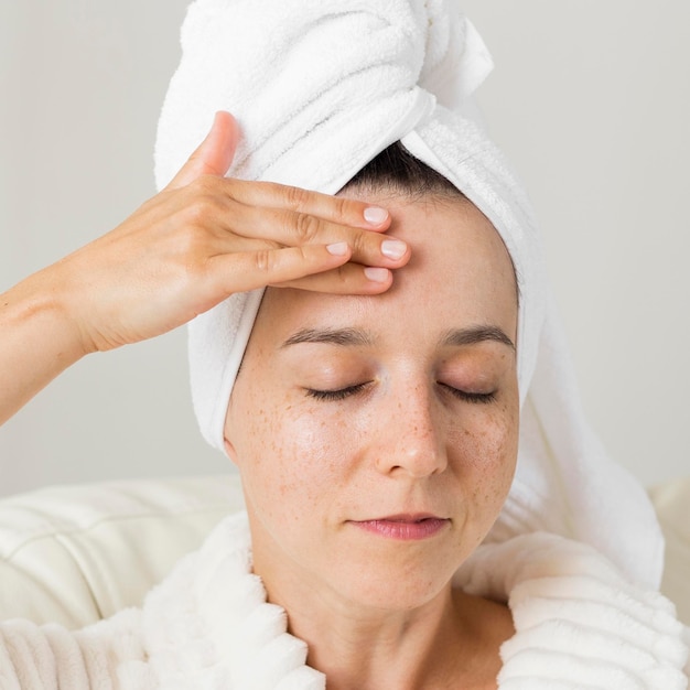 Close-up woman applying cream on her face