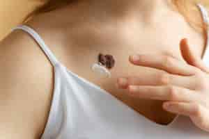 Free photo close up woman applying cream on mole