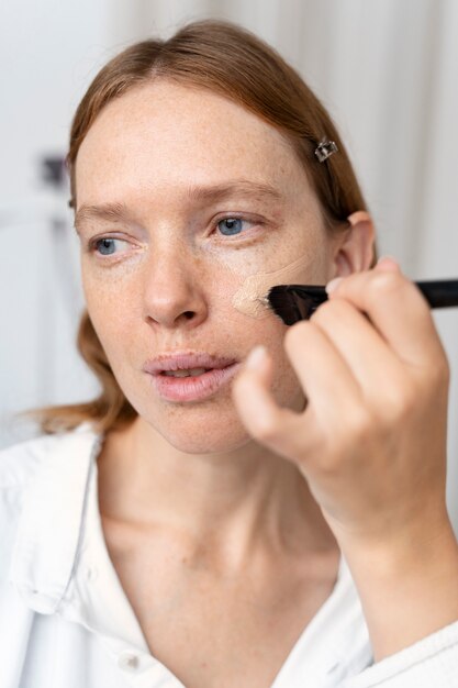 Close up woman applying foundation