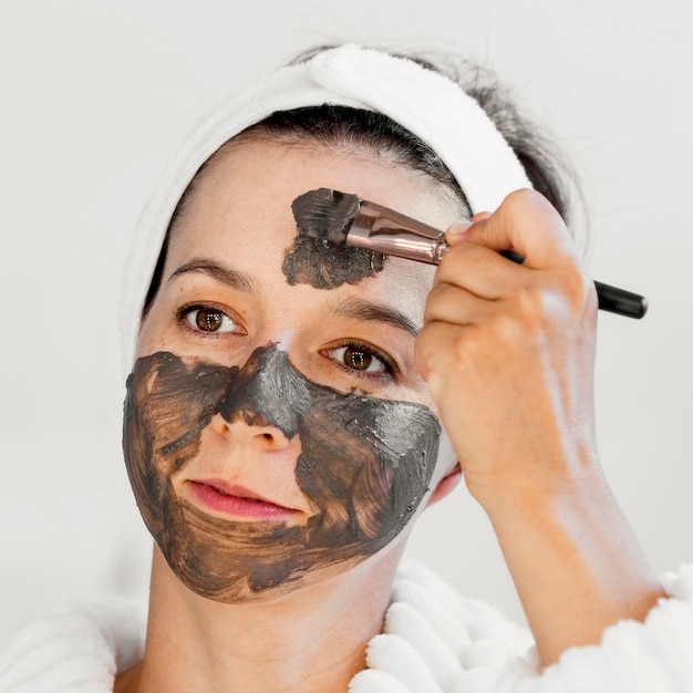 Close-up woman applying spa organic facial mask