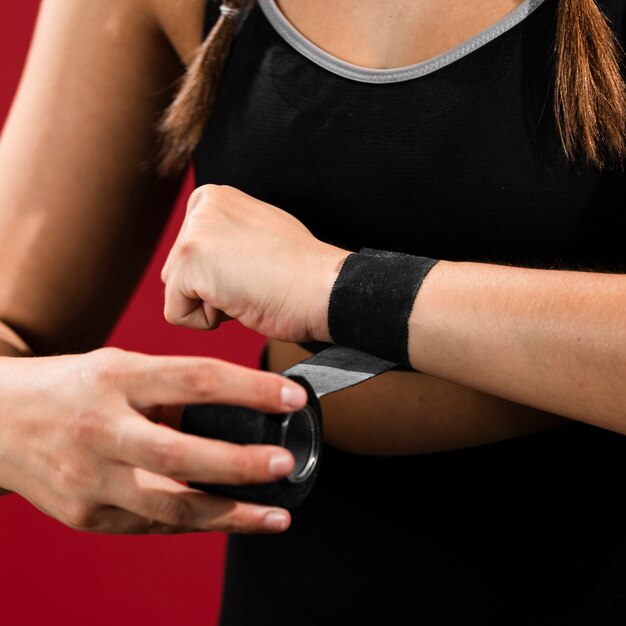 Close-up woman bandaging her arms