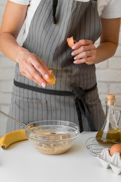 Close-up woman breaking egg over bowl