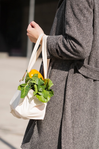 Donna del primo piano che porta borsa ecologica con le verdure