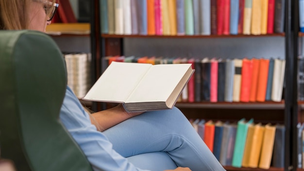 Foto gratuita donna del primo piano sulla lettura della sedia