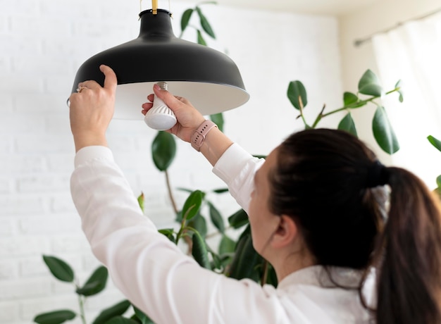 Free photo close up woman changing lightbulb