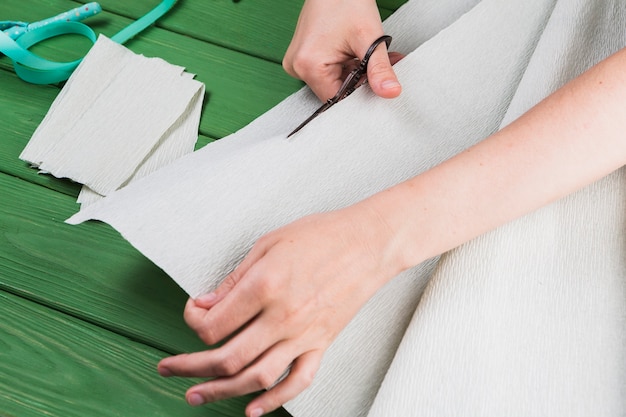 Free photo close-up of a woman cutting crepe paper with scissor