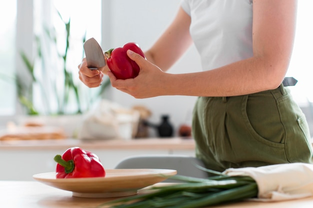 Close-up woman cutting  organic red peppers