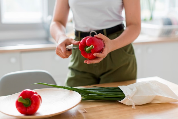 Close-up woman cutting red peppers