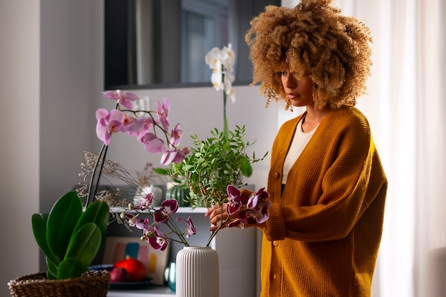 Foto gratuita primo piano su una donna che decora la sua casa con orchidee