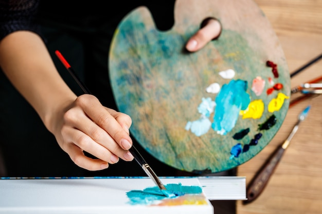 Free photo close up of woman drawing with oil paints on canvas