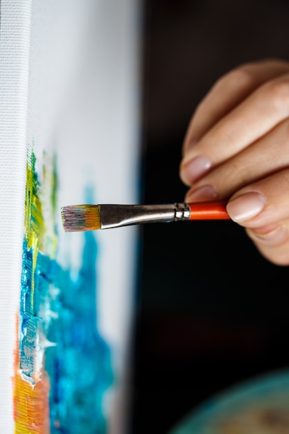 Close up of woman drawing with oil paints on canvas