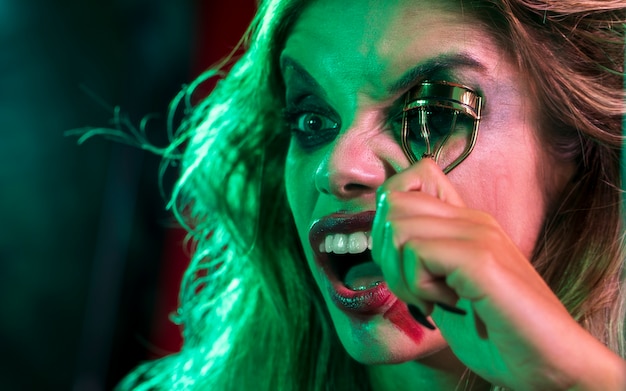 Close-up woman dressed as joker using a eyelash curler