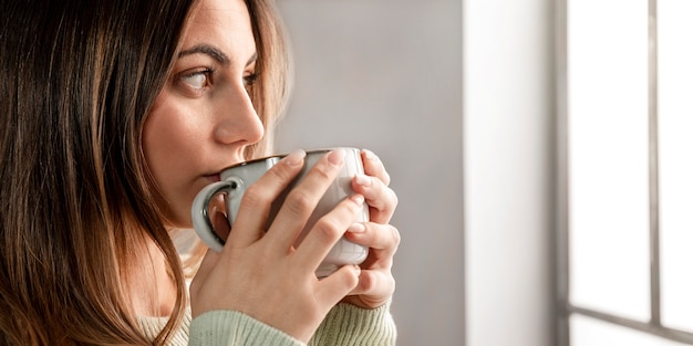 Foto gratuita donna del primo piano che beve dalla tazza