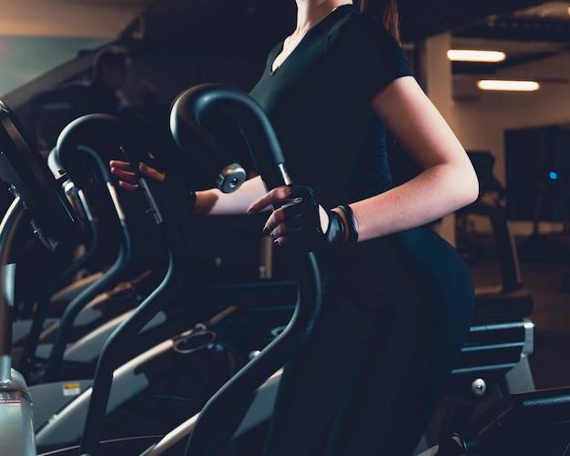 Close-up of a woman exercising on elliptical cardio machine