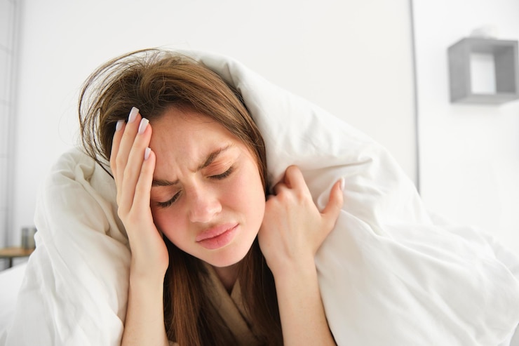 Free Photo close up of woman feeling unwell at home lying in bed under white blankets and frowning touching