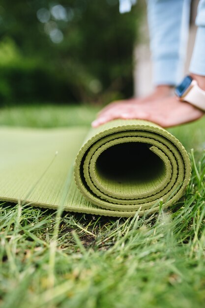 Free photo close-up of woman folding roll fitness or yoga mat after working out in the park