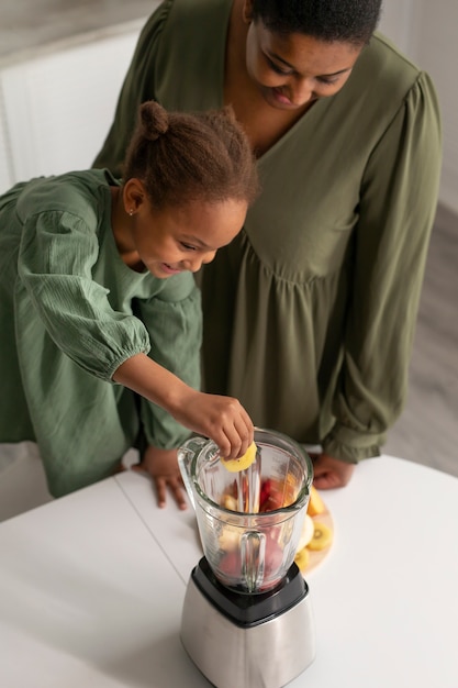 Close up woman and girl making smoothie