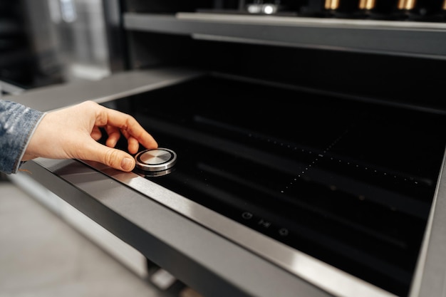 Close up of a woman hand checking new stove in a hypermarket