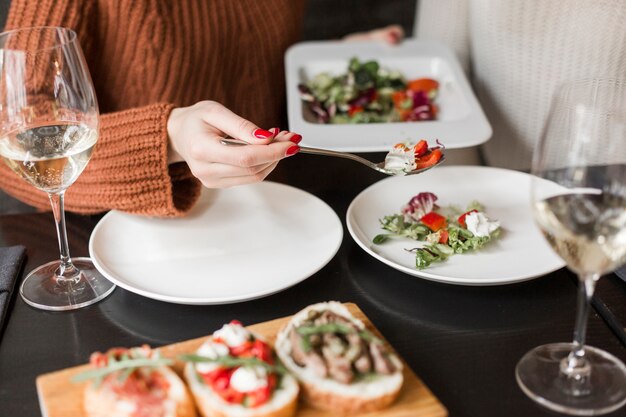 Close-up woman having salad and wine