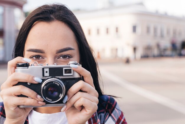 Close-up of woman hiding mouth with holding retro camera